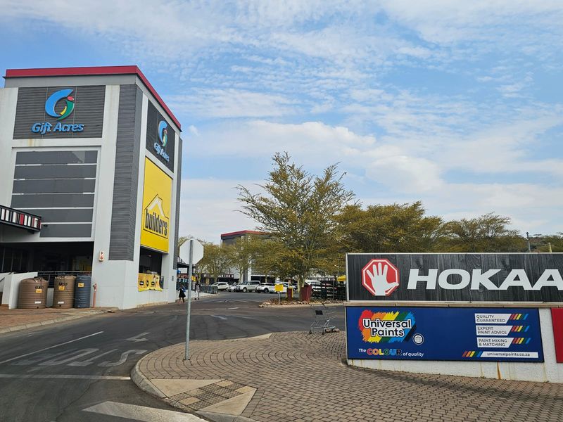 Front view of a commercial retail center featuring modern metal cladding, paved access areas, and prominent tenant signage.