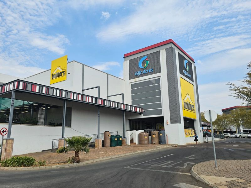 Front exterior view of a retail building featuring prominent signage, a covered walkway, and paved access area.