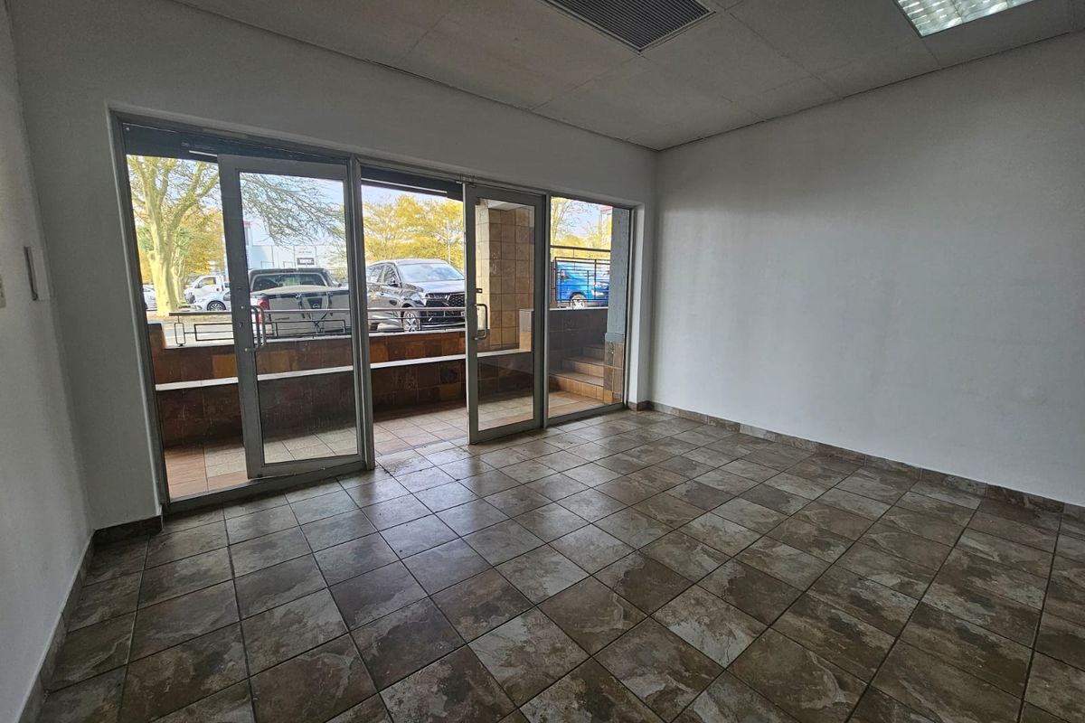 Empty retail entrance area featuring tiled flooring, glass sliding doors, and recessed ceiling lighting, providing a clean and versatile space for business use.