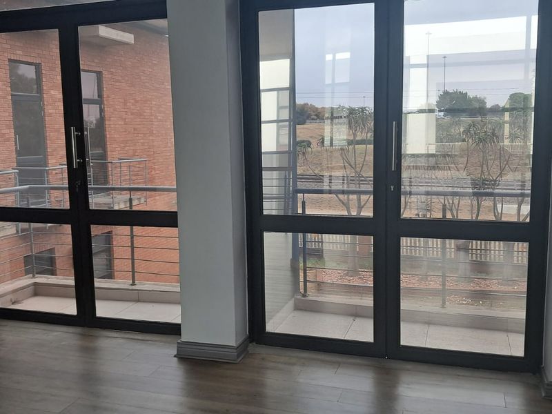 Office space featuring large glass doors leading to private balconies, providing natural light and views of the surrounding area.