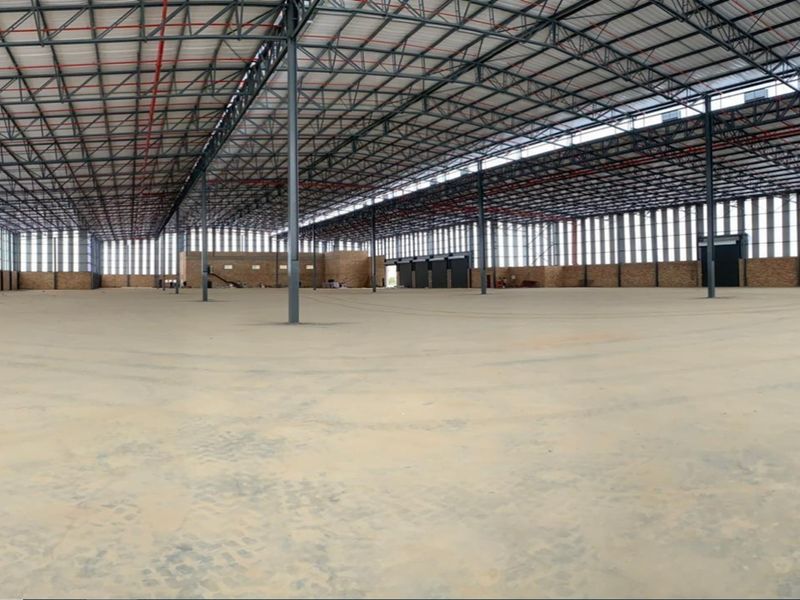 Expansive industrial warehouse space featuring a high-clearance steel portal frame, concrete flooring, and integrated fire sprinkler system.