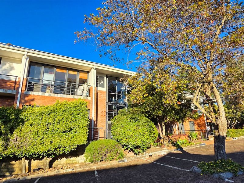 Exterior view of Block A office building featuring brick facade, balconies with metal railings, and adjacent paved parking area with established landscaping.