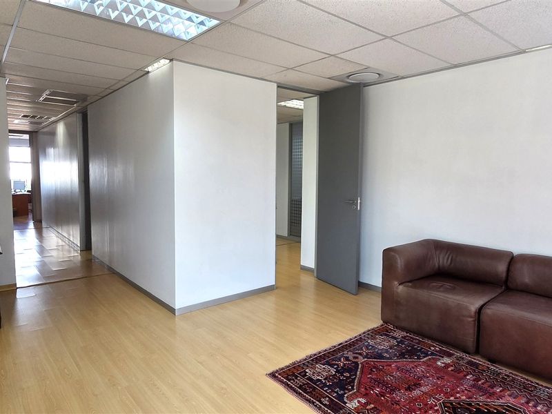 A functional office space featuring laminate flooring, a suspended ceiling with recessed lighting, and neutral wall finishes, providing a clean and professional work environment.
