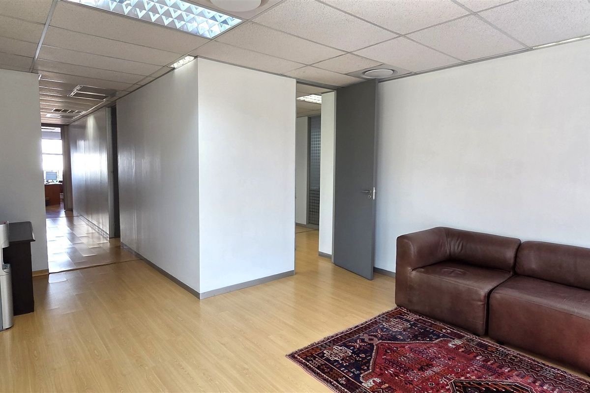 A functional office space featuring laminate flooring, a suspended ceiling with recessed lighting, and neutral wall finishes, providing a clean and professional work environment.