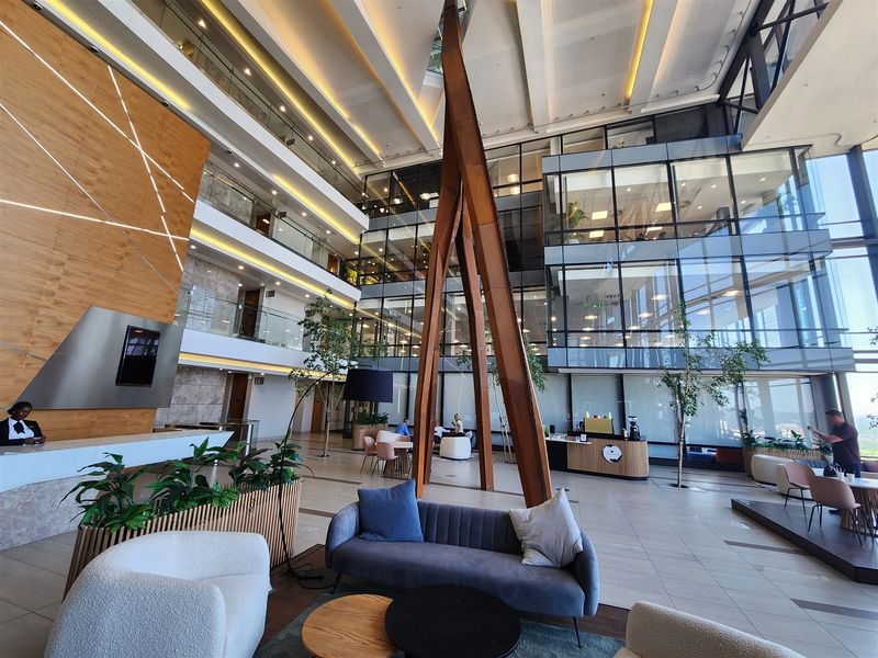 Spacious modern office atrium featuring high ceilings, glass curtain walls, and a professional reception area with contemporary finishes.