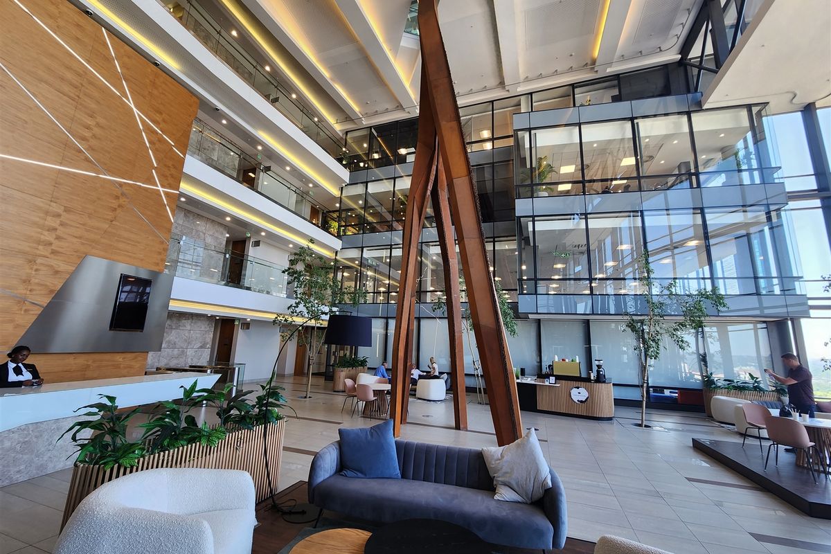 Spacious modern office atrium featuring high ceilings, glass curtain walls, and a professional reception area with contemporary finishes.