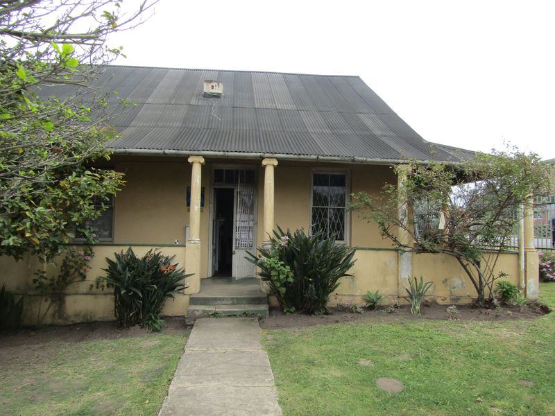 Front elevation of a commercial property featuring a corrugated metal roof, covered veranda with structural columns, and a concrete entrance walkway.