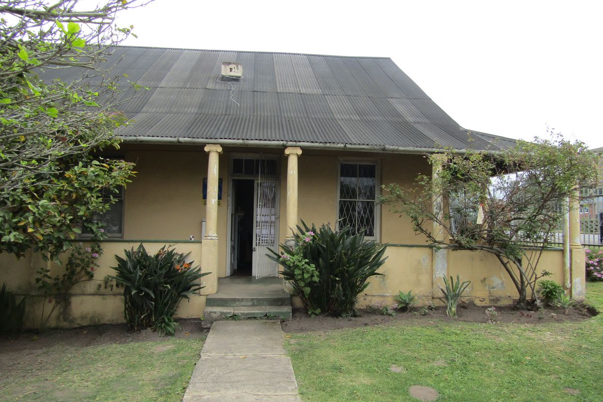Front elevation of a commercial property featuring a corrugated metal roof, covered veranda with structural columns, and a concrete entrance walkway.