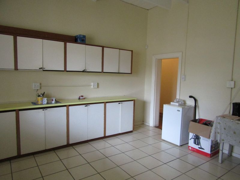 A functional kitchen area featuring built-in cabinetry, laminate countertops, and tiled flooring, offering a blank canvas for potential modernization and renovation.