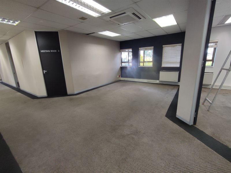 An empty office space featuring suspended ceilings, recessed lighting, ducted air conditioning, and carpeted flooring, suitable for a professional workspace.