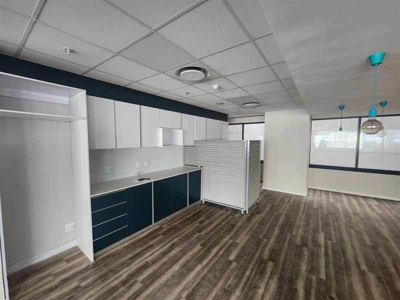 A modern, open-plan office space featuring built-in cabinetry, durable laminate flooring, and a clean suspended ceiling with integrated lighting.