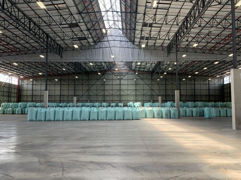 Spacious industrial warehouse featuring high-clearance steel truss roofing, polished concrete flooring, and ample overhead lighting, suitable for large-scale storage or manufacturing operations.