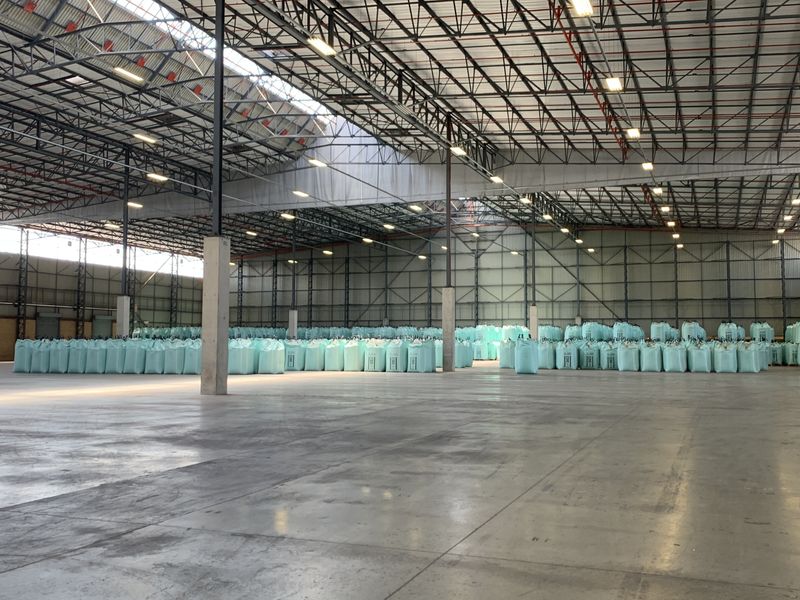 Expansive industrial warehouse space featuring high-clearance steel truss roofing, polished concrete flooring, and functional overhead industrial lighting.