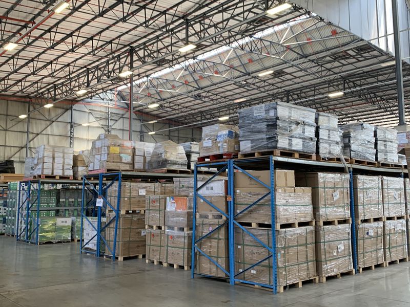 Spacious industrial warehouse facility featuring high-clearance ceilings, exposed steel trusses, durable concrete flooring, and extensive integrated pallet racking systems for storage.