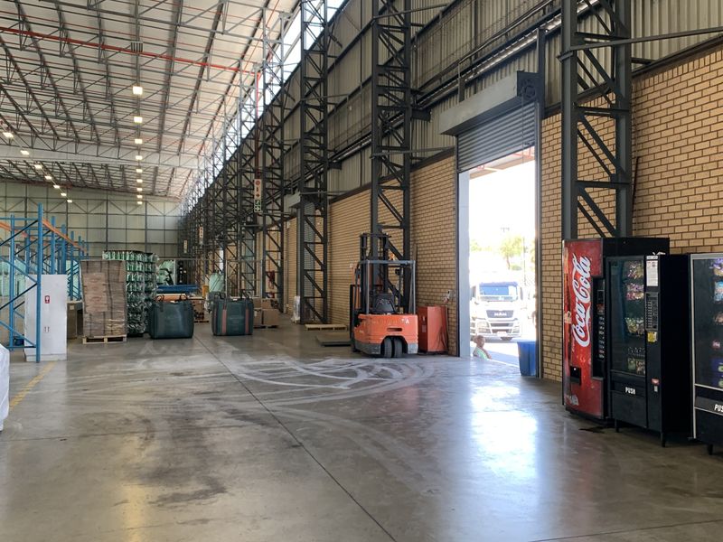Spacious industrial warehouse facility featuring high-clearance steel portal frame construction, concrete flooring, and a large roller shutter door for efficient loading access.