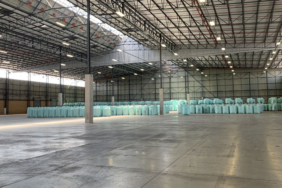 Spacious industrial warehouse featuring high-clearance steel truss roofing, polished concrete flooring, and integrated fire sprinkler systems, suitable for large-scale storage or logistics operations.