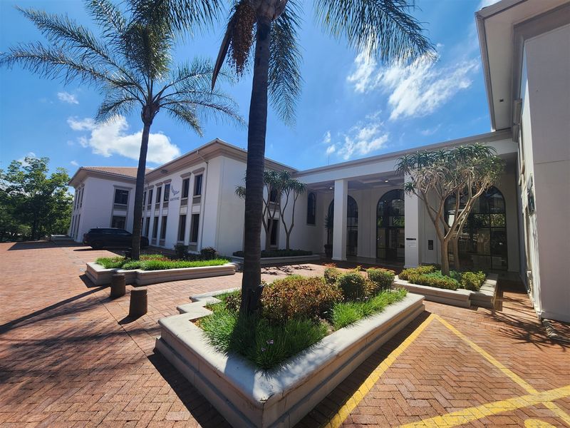 Front exterior view of a professional office building featuring a brick-paved entrance, raised concrete planters, and an arched portico.