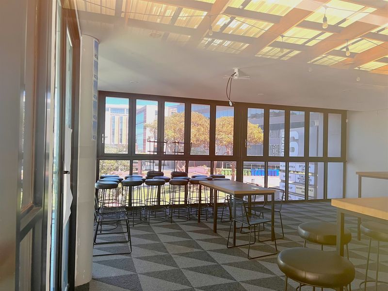 Modern office space featuring large windows, exposed timber ceiling beams, and patterned carpeting, offering a bright and open work environment.