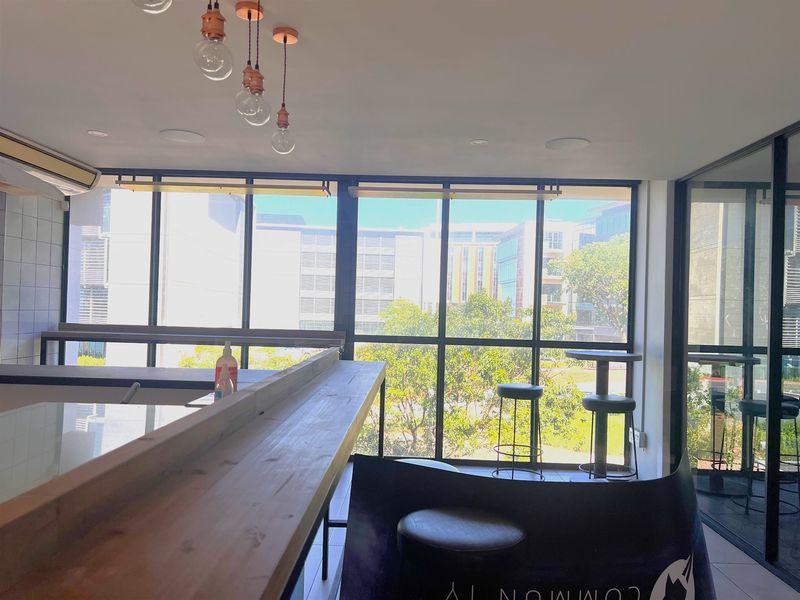 Modern office space featuring floor-to-ceiling windows, built-in wooden counter, and glass partitions, offering a bright and professional work environment.