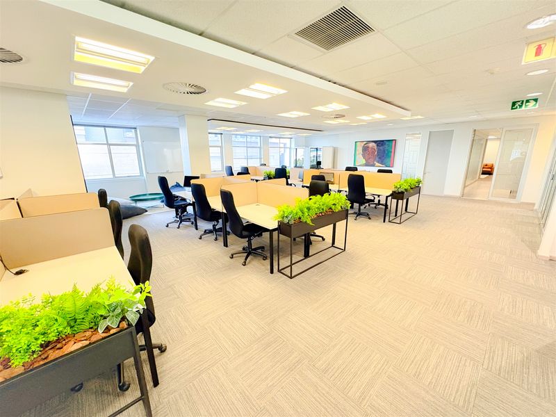 Spacious open-plan office area featuring modern carpet tiles, recessed ceiling lighting, integrated air conditioning, and glass partition doors for a professional workspace environment.