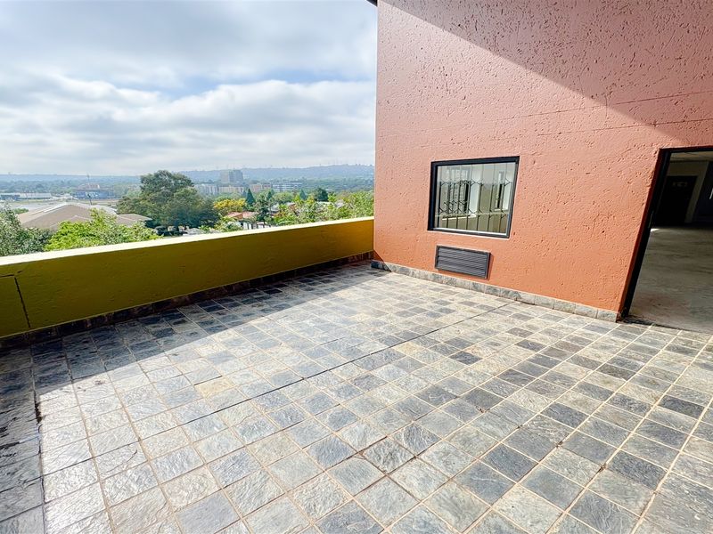 Spacious outdoor balcony featuring tiled flooring, a parapet wall, and scenic elevated views, providing an ideal space for an office break area.