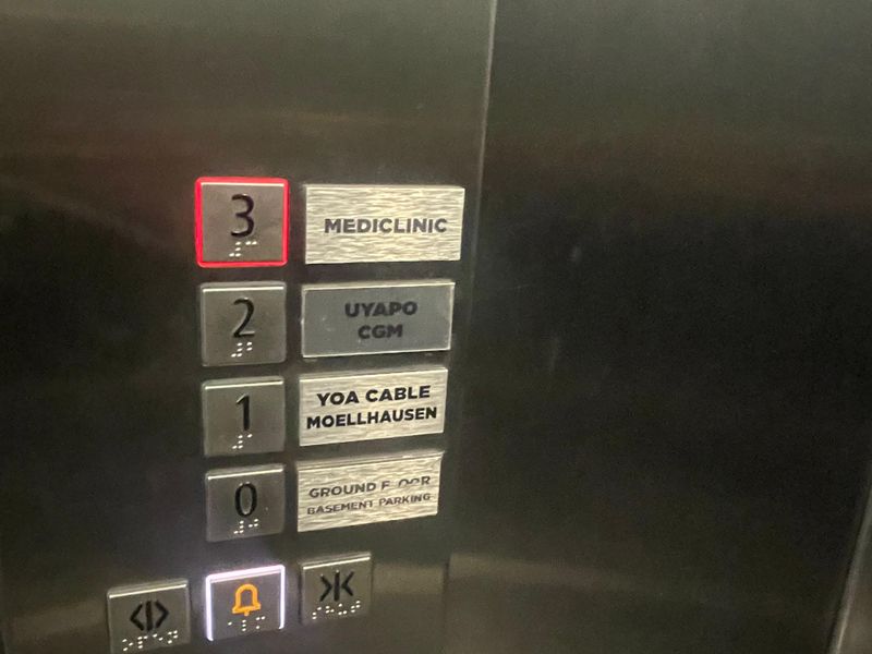Close-up view of a modern stainless steel elevator control panel with tactile floor buttons and braille signage for office building levels.