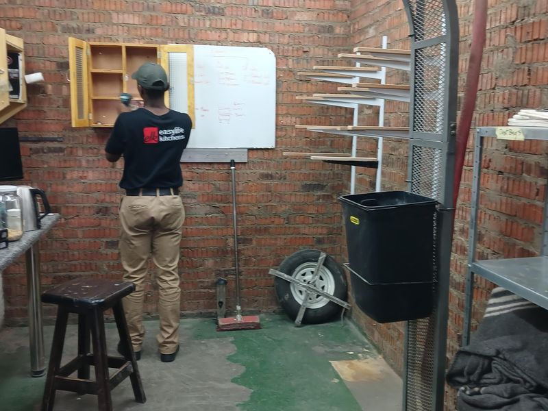A utility workspace featuring exposed brick walls, industrial shelving units, and a wall-mounted cabinet, suitable for workshop or storage use.