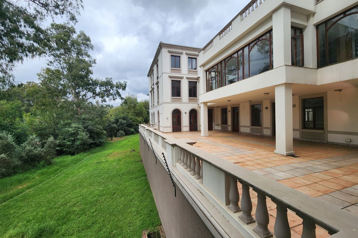 Spacious rear exterior patio featuring tiled flooring, a classic balustrade, and covered terrace area overlooking the surrounding garden and landscape.