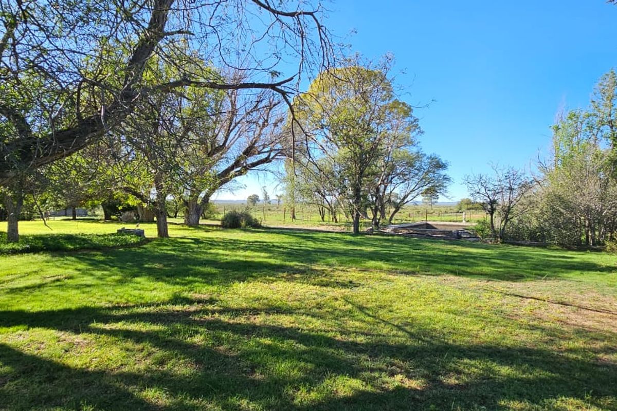 A spacious, well-maintained garden area on the farm property, featuring mature trees and expansive green lawn space.