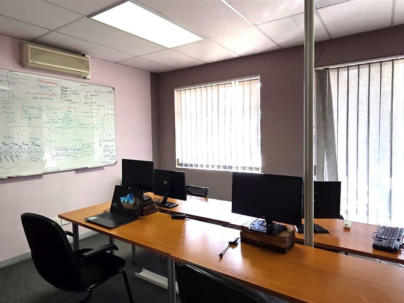 Functional office space featuring drop ceilings, recessed lighting, wall-mounted air conditioning, and vertical blinds, providing a practical work environment.