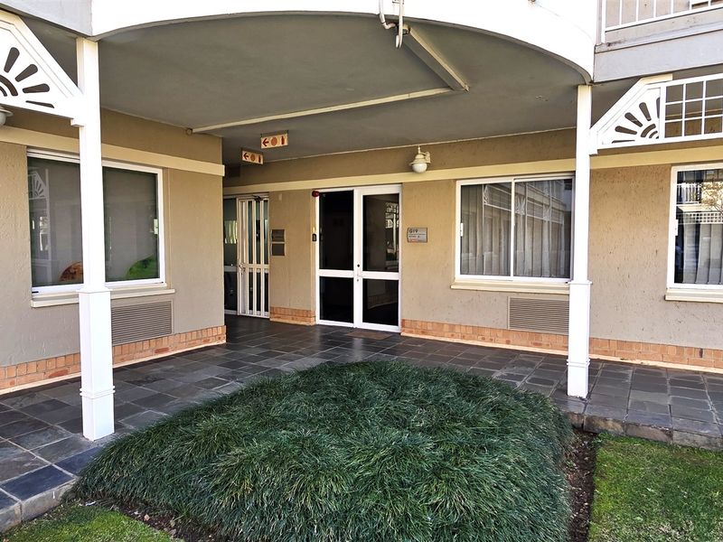 Front entrance area of the office building featuring a covered patio with slate tiling, security access points, and well-maintained exterior finishes.