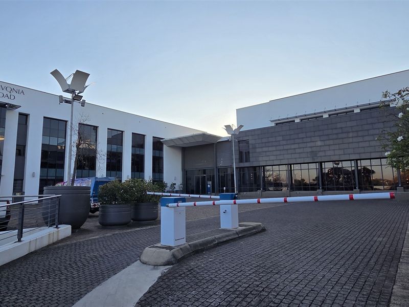 Front exterior view of a modern commercial office building at 345 Rivonia Road, featuring a paved driveway and secure access boom gate.