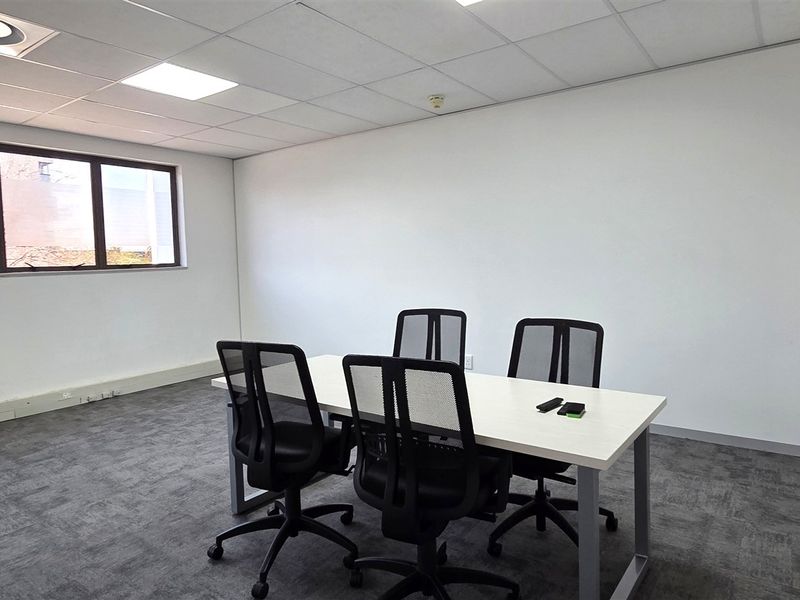 A functional office space featuring a suspended ceiling, recessed lighting, and carpeted flooring, providing a clean and professional work environment.