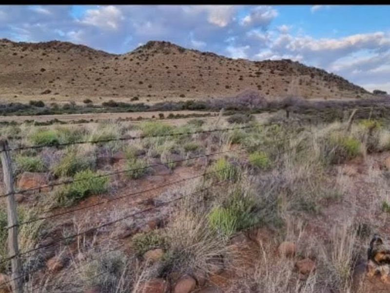 Expansive rural landscape view featuring natural vegetation, rolling hills, and traditional wire farm fencing.
