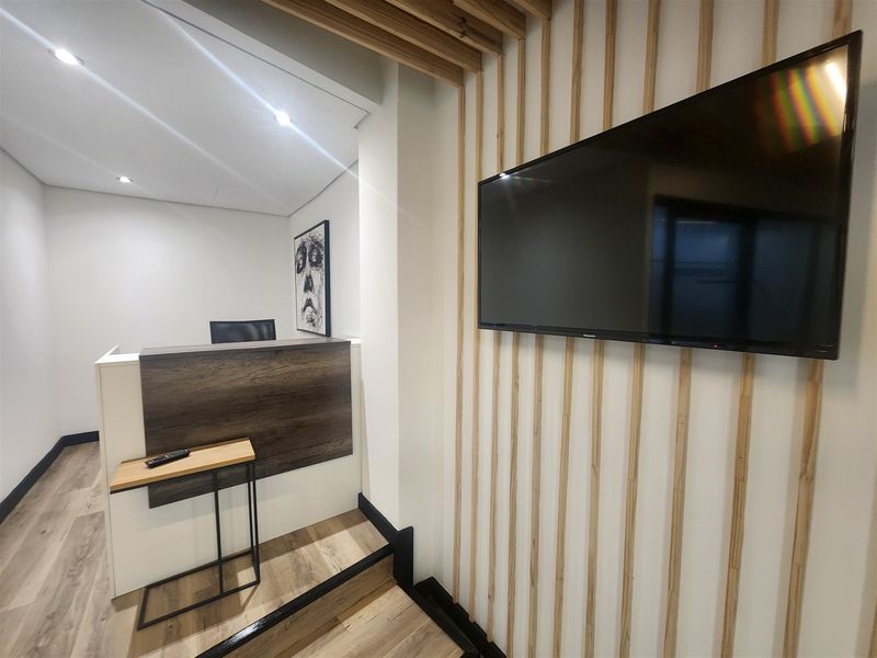 Modern office reception area featuring a contemporary reception desk, timber slat wall detailing, and high-quality laminate flooring with recessed lighting.
