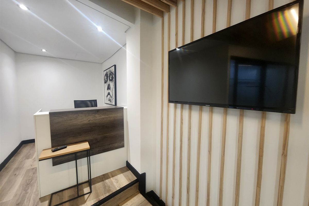Modern office reception area featuring a contemporary reception desk, timber slat wall detailing, and high-quality laminate flooring with recessed lighting.