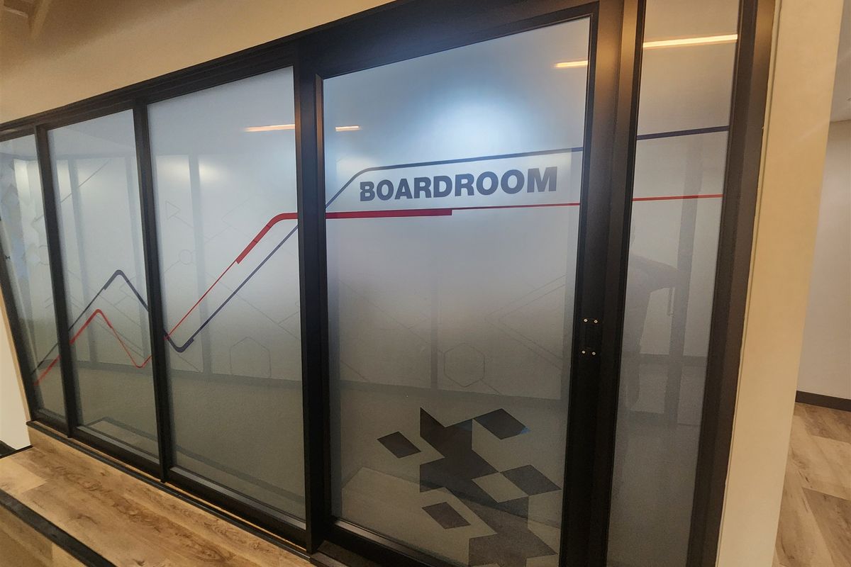 Modern office boardroom featuring a sleek black aluminum frame with frosted glass partitioning and durable laminate flooring.