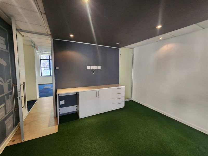 A modern office space featuring built-in cabinetry, recessed lighting, and a glass partition, providing a clean and professional work environment.