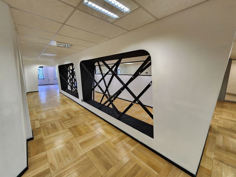 Modern open-plan office space featuring high-quality parquet flooring, suspended ceilings with recessed lighting, and unique decorative structural steel wall accents.