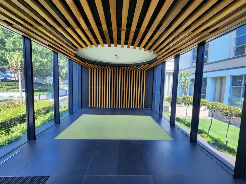 Modern office entrance lobby featuring floor-to-ceiling glass walls and a striking timber slat ceiling and wall design.