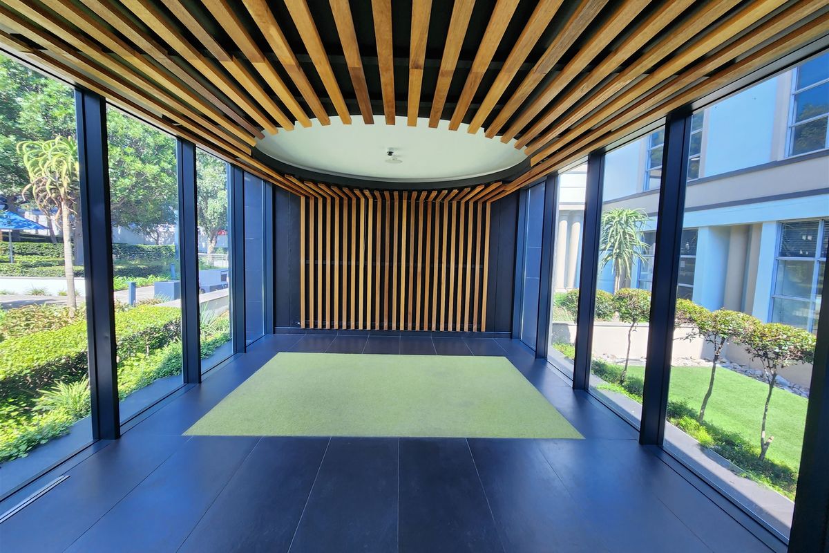 Modern office entrance lobby featuring floor-to-ceiling glass walls and a striking timber slat ceiling and wall design.