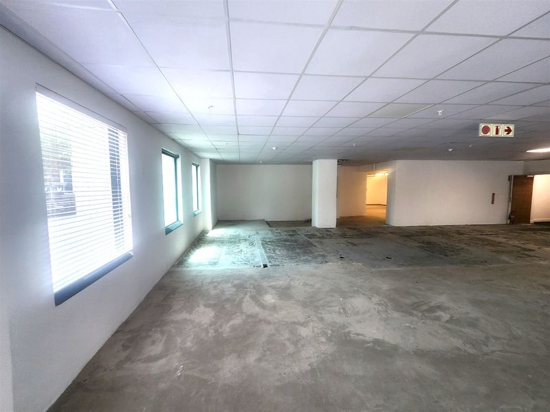 A spacious, vacant office area featuring a suspended ceiling, venetian blinds, and unfinished concrete flooring, ready for custom fit-out and flooring installation.