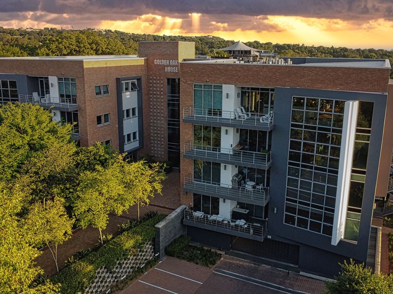Aerial view of Golden Oak House, a modern multi-story office building featuring brick and glass facade with integrated balconies and on-site parking.