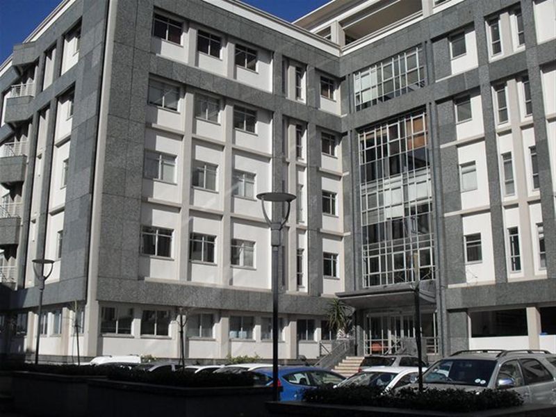 A multi-story office building featuring a modern facade with granite cladding, large glass windows, and a prominent entrance canopy.