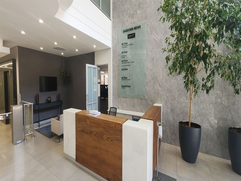 Modern office building lobby featuring a professional reception desk, stone feature wall, directory signage, and secure access turnstiles.
