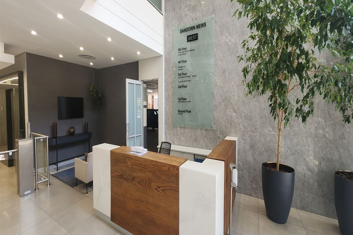 Modern office building lobby featuring a professional reception desk, stone feature wall, directory signage, and secure access turnstiles.