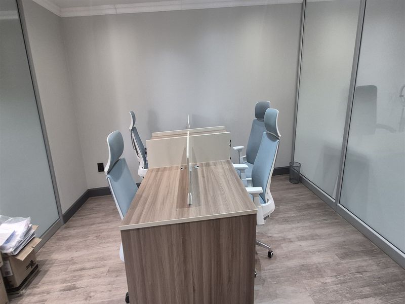 A modern office space featuring glass partition walls, wood-look laminate flooring, and clean neutral finishes, suitable for a professional work environment.