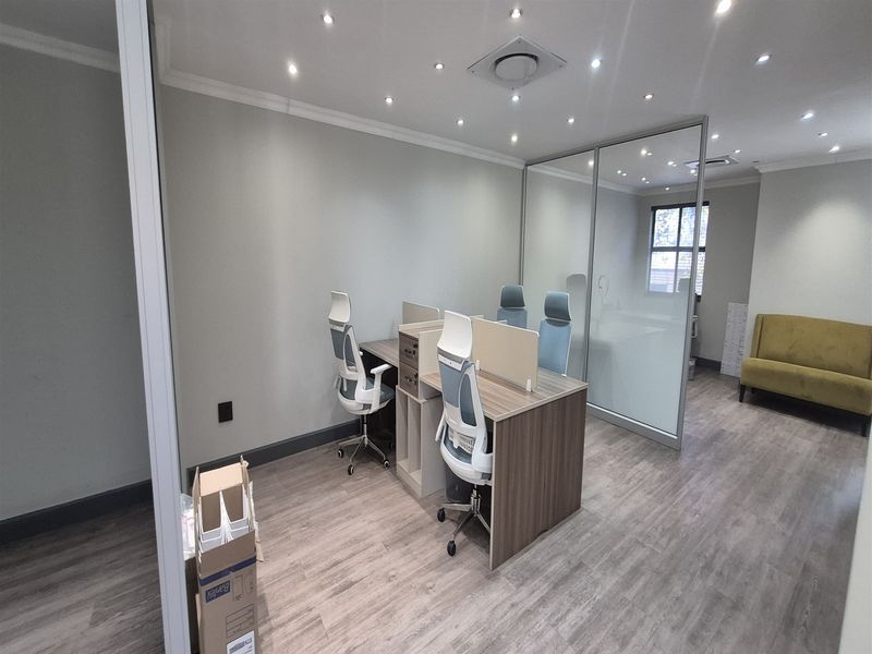 Modern office space featuring glass partitioning, recessed downlighting, and durable laminate flooring, providing a professional and well-lit work environment.
