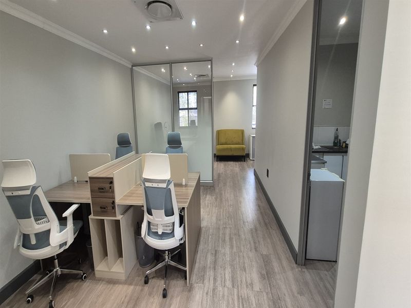 Modern office space featuring laminate flooring, recessed lighting, and a glass partition, providing a clean and professional work environment.