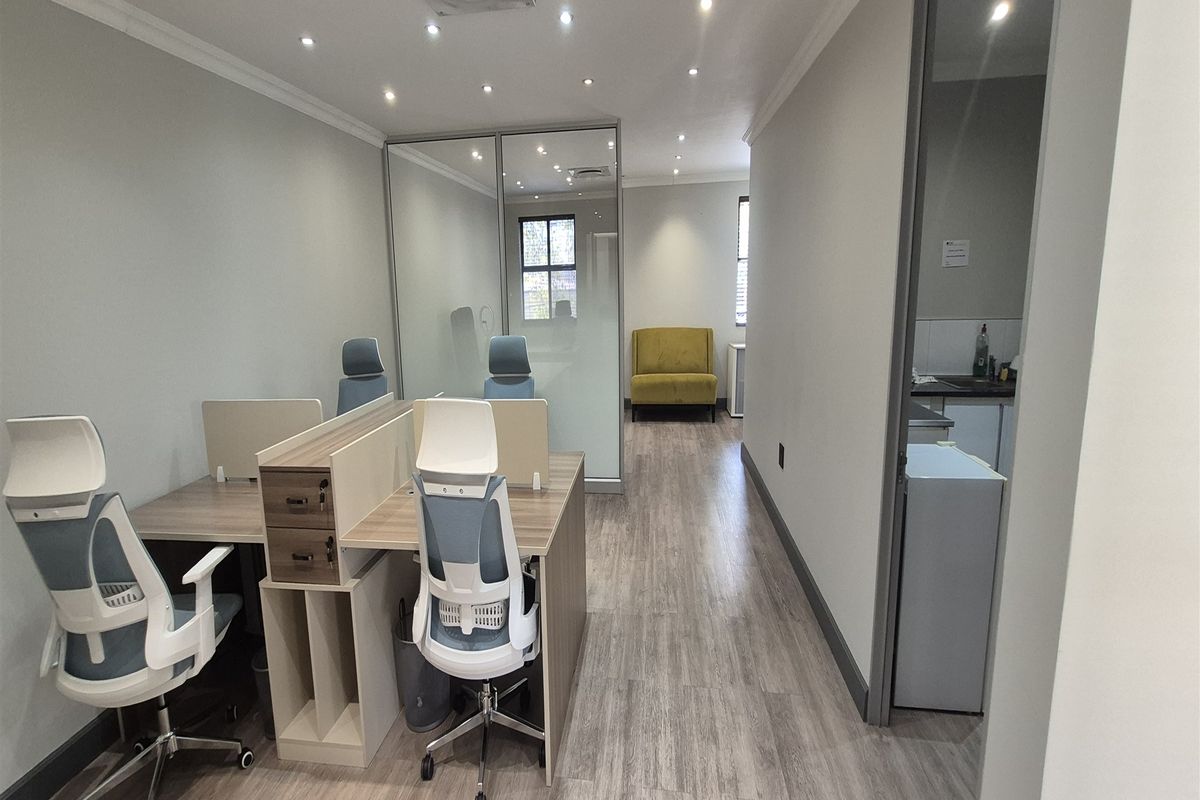 Modern office space featuring laminate flooring, recessed lighting, and a glass partition, providing a clean and professional work environment.